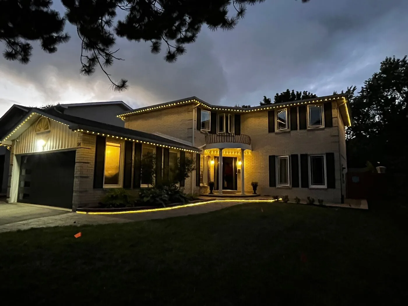 Home with red permanent LED roofline lighting at dusk