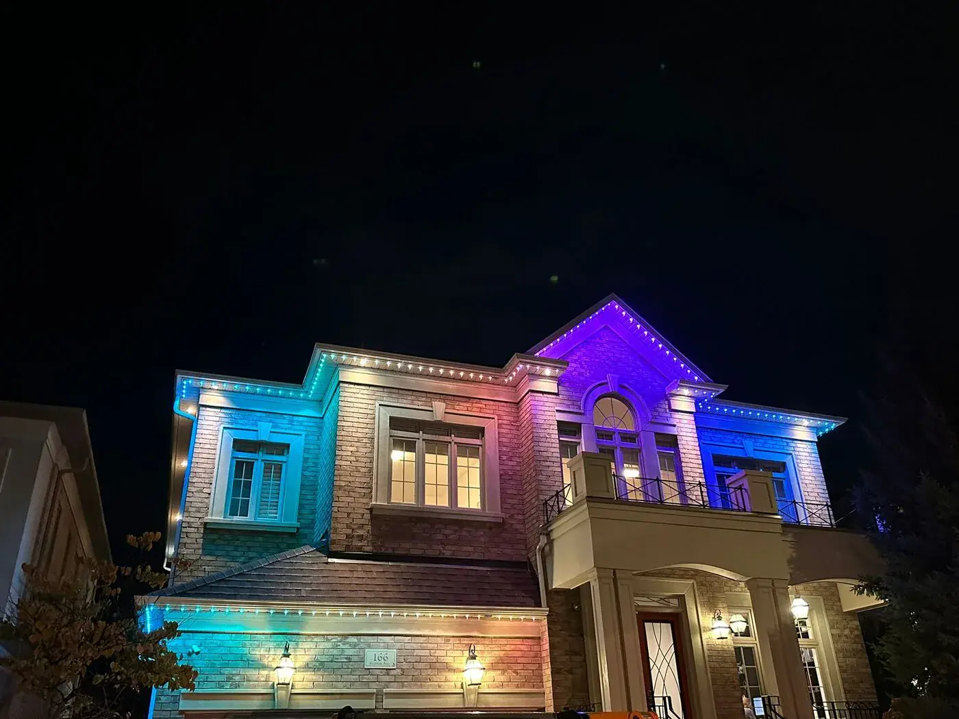 Large home with multicolour teal and purple permanent LED roofline lighting