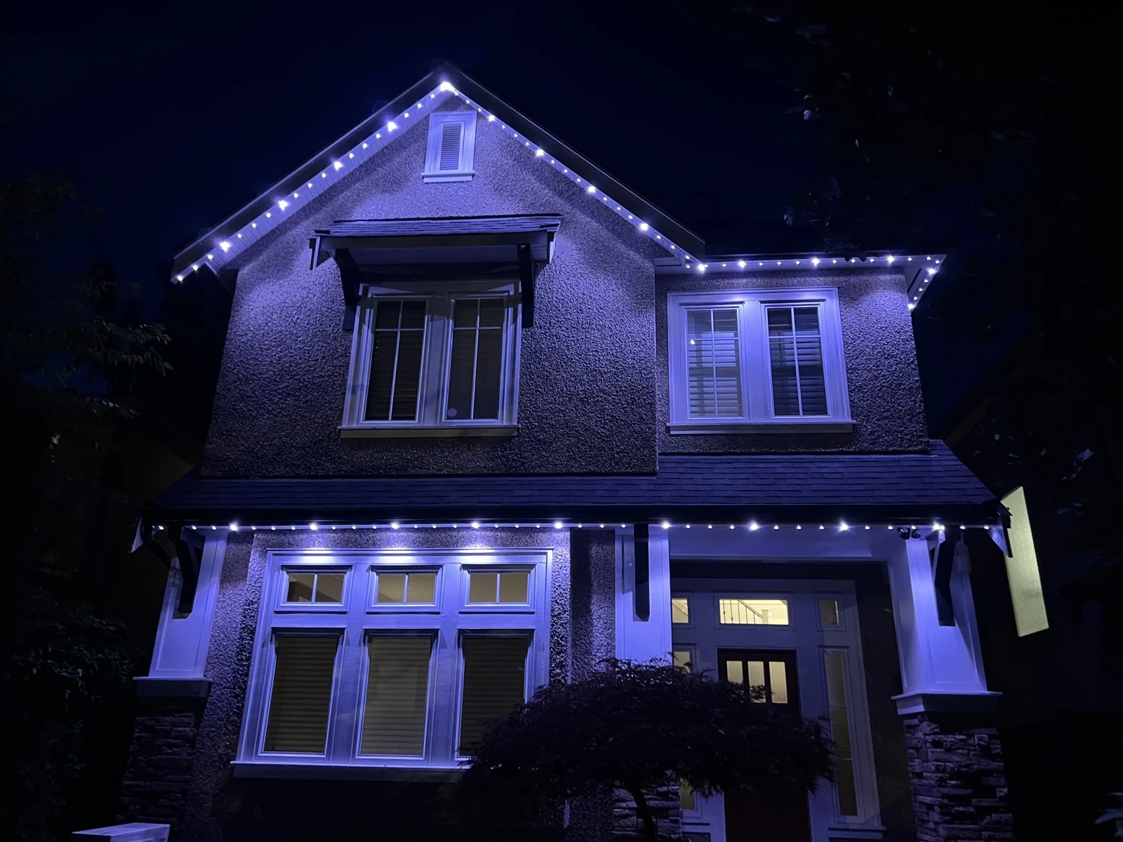 Real Vancouver home with cool white and purple permanent roofline lights glowing at night