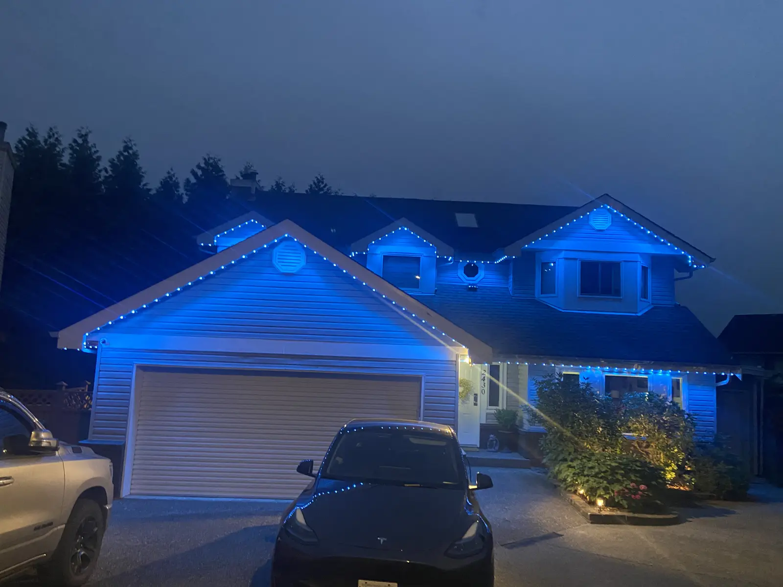 Home with blue permanent LED roofline lighting at dusk
