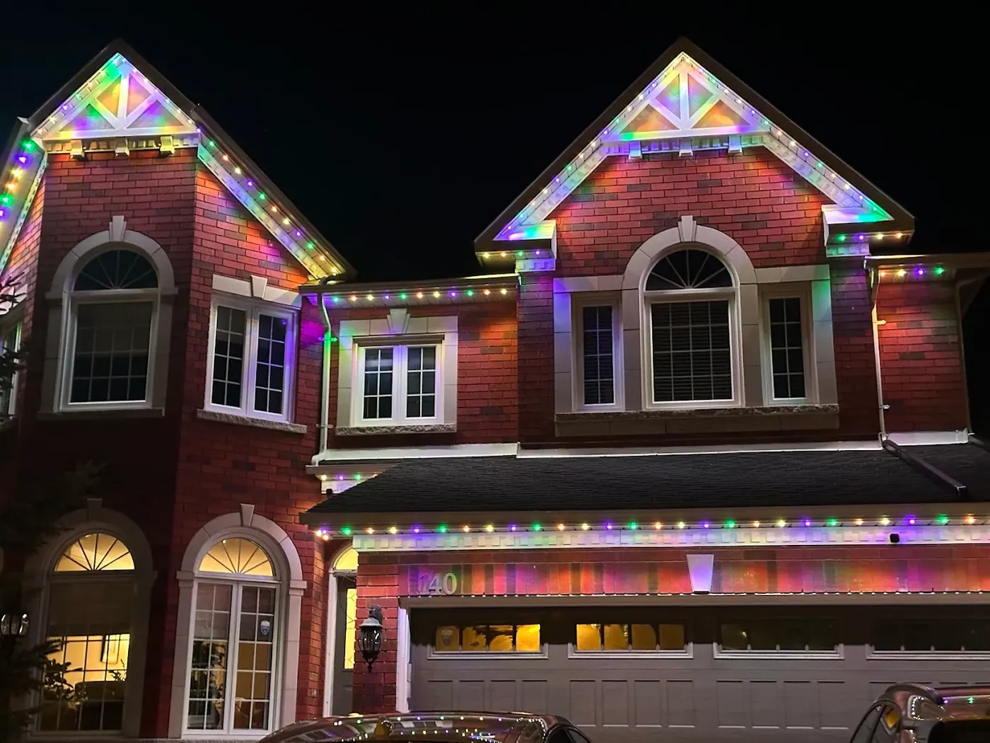 Home with permanent outdoor LED lights in rainbow colours tracing rooflines, peaks, and soffits at night by Vancouver Glow