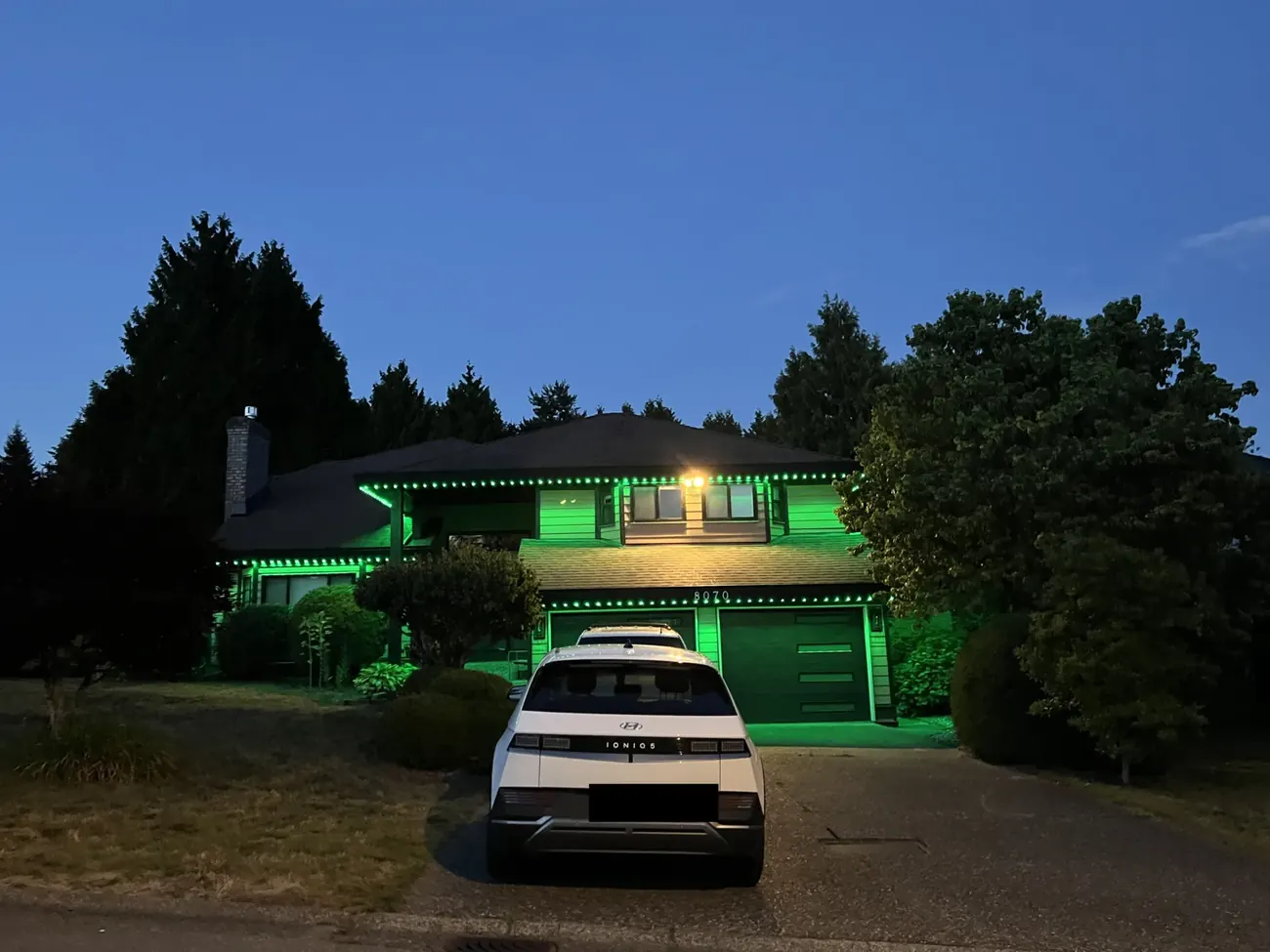 Home with green permanent LED roofline lighting at dusk