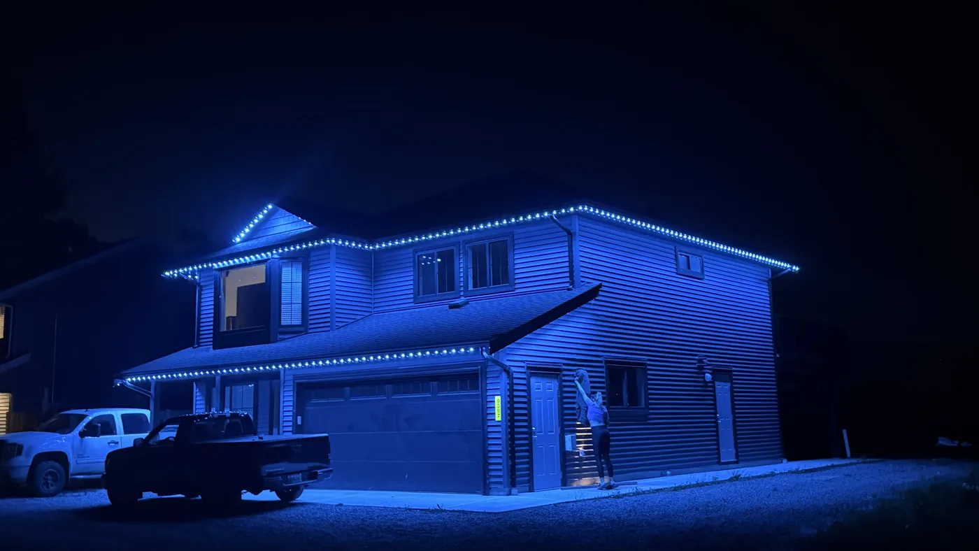 Greater Vancouver home with bright blue permanent LED roofline lighting at night