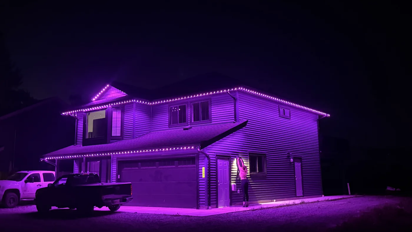 Greater Vancouver home with purple permanent LED roofline lighting at night