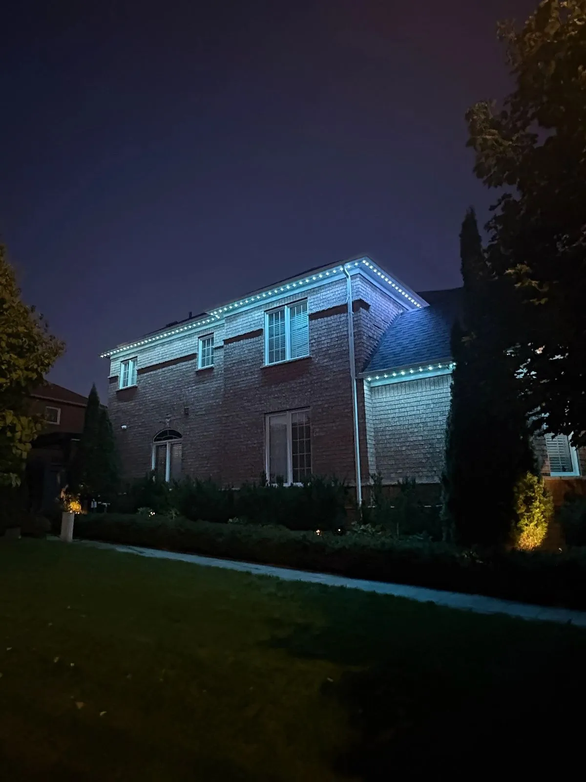 Vancouver home with teal and blue permanent LED soffit lighting at night
